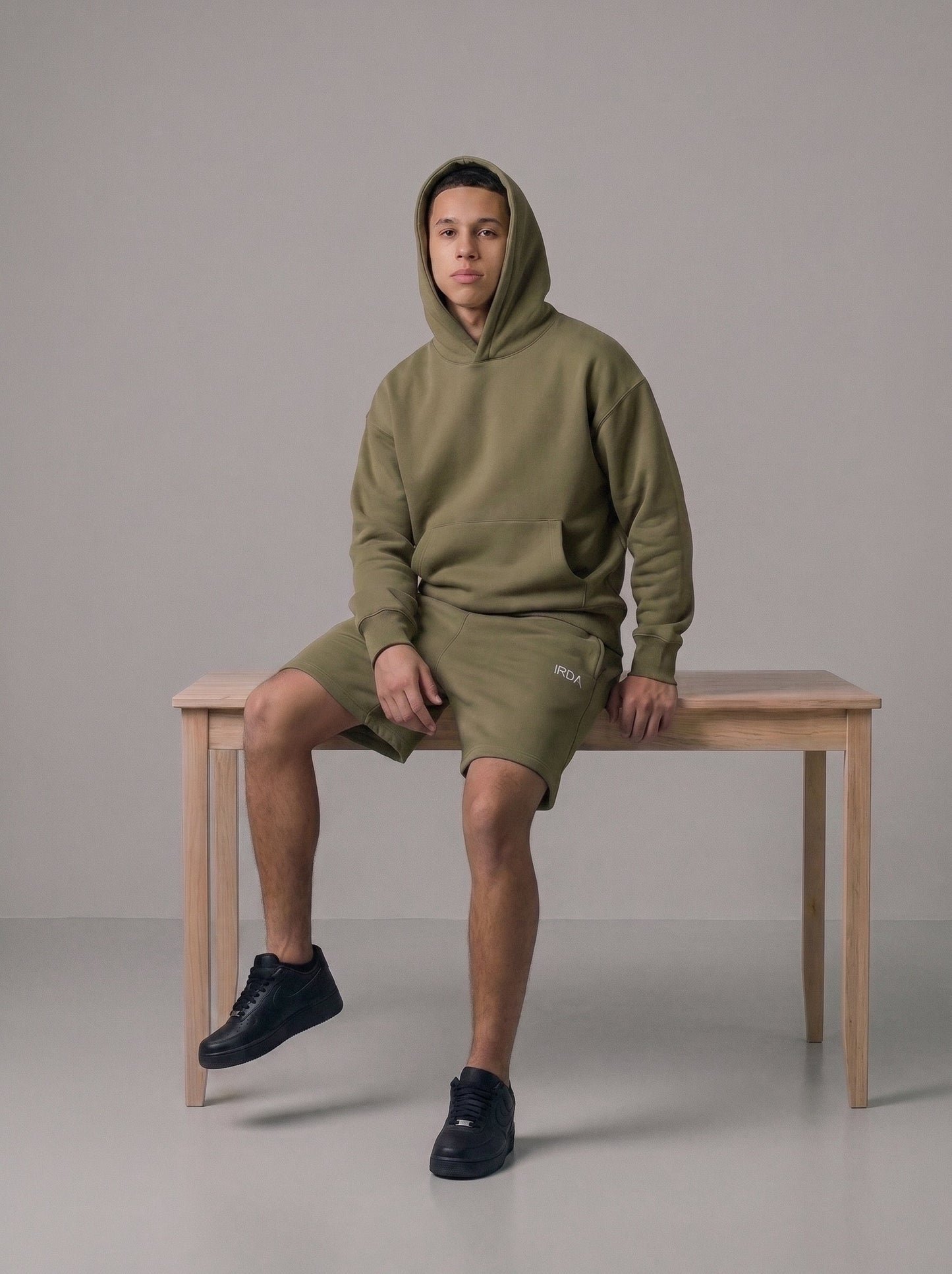 Men's oversized fleece hoodie and shorts set in army green, full body on bench