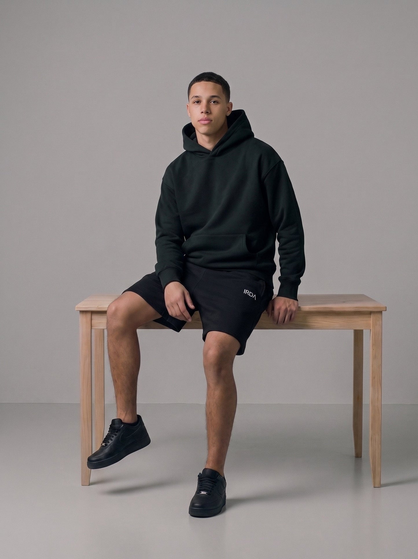 Men's oversized fleece hoodie and shorts set in black, full body on bench