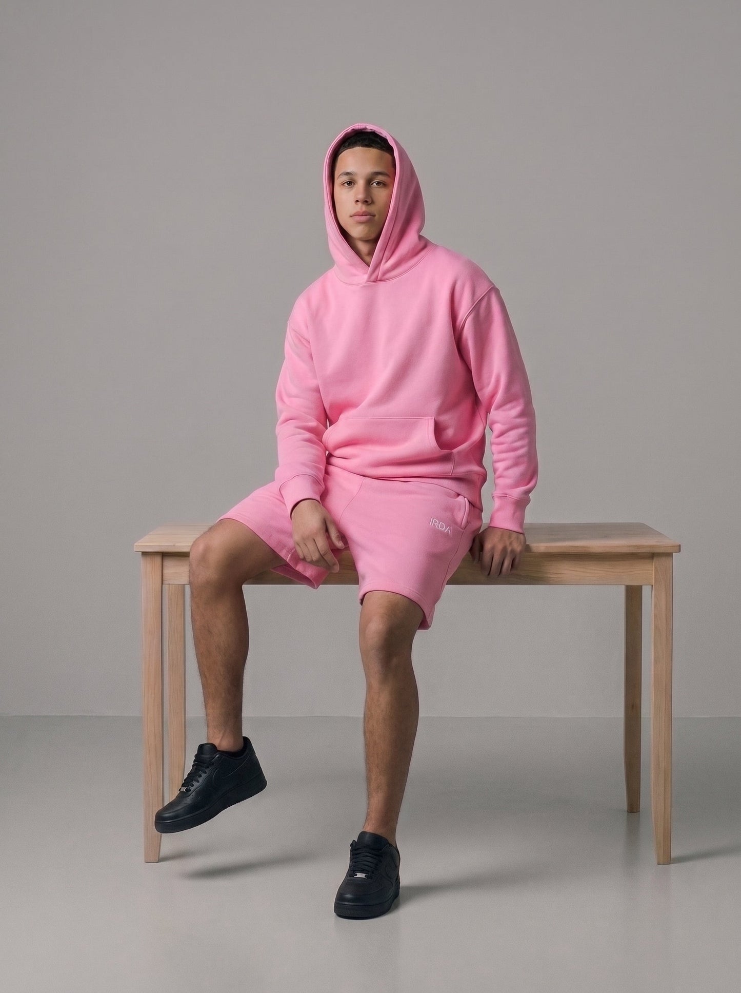 Men's oversized fleece hoodie and shorts set in pink, full body on bench