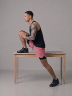 Men's 2-in-1 gym shorts in pink with built-in liner, worn on bench