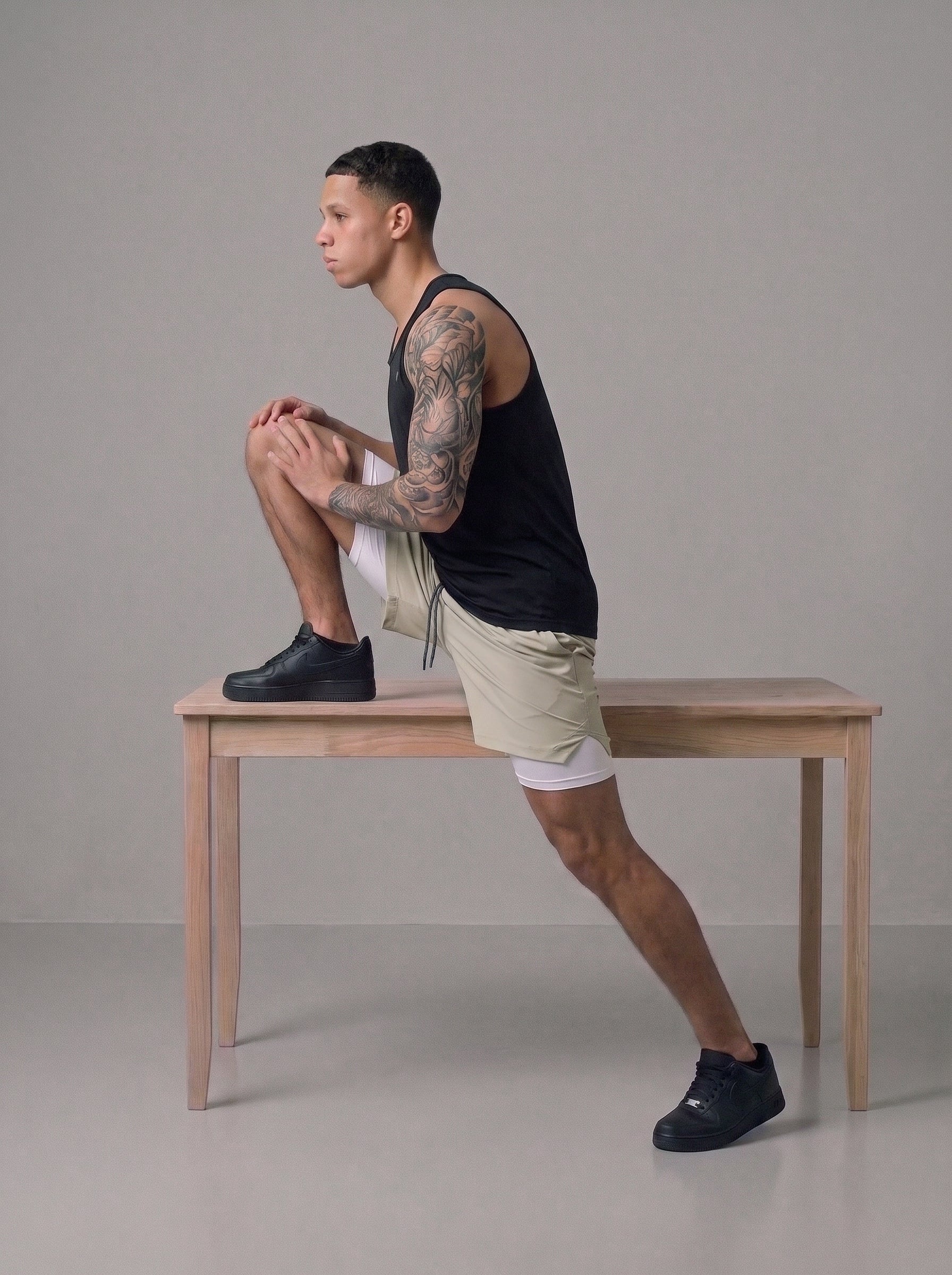 Men's 2-in-1 gym shorts in khaki with built-in liner, worn on bench