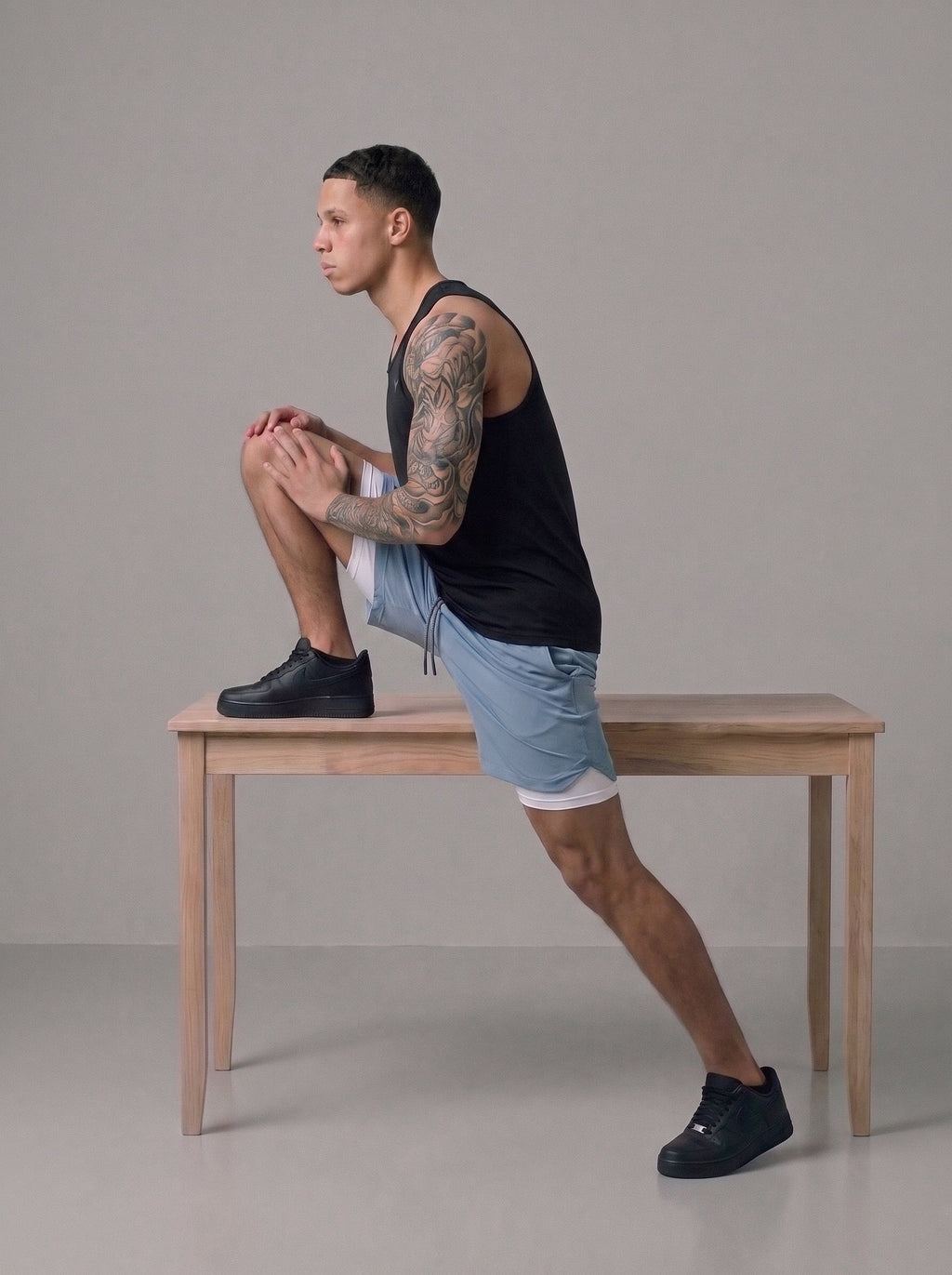 Men's 2-in-1 gym shorts in light blue with built-in liner, worn on bench