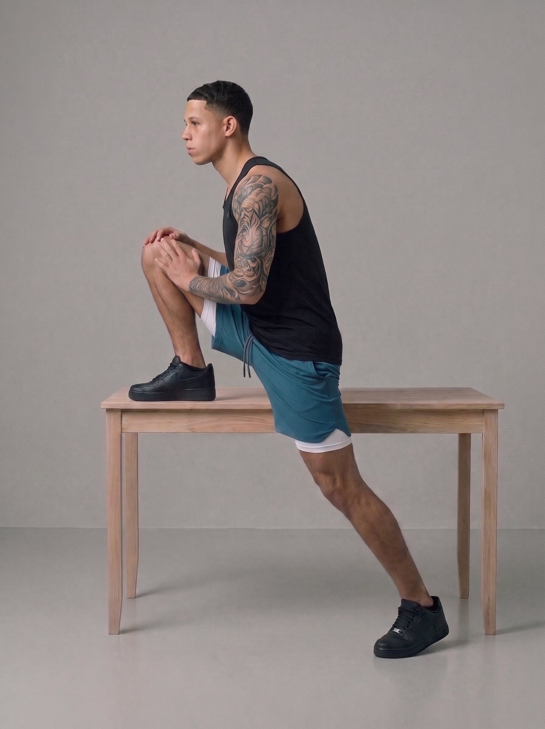 Men's 2-in-1 gym shorts in teal with built-in liner, worn on bench