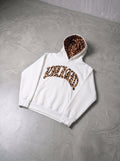 Leopard trim hoodie in white, laid flat on concrete floor