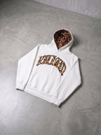 Leopard trim hoodie in white, laid flat on concrete floor