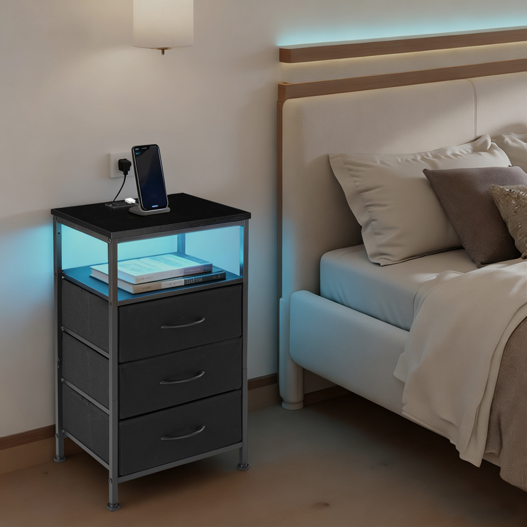 Black nightstand with LED lights beside a bed